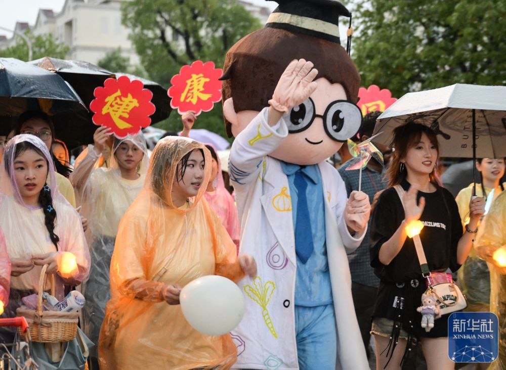 6月21日，华中农业大学学生在校园里冒雨巡游。2